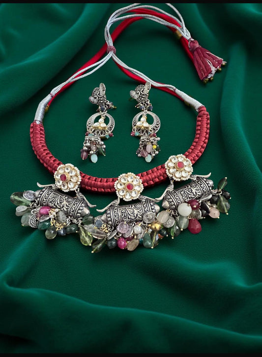 Ornate necklace and earrings set on a green fabric background