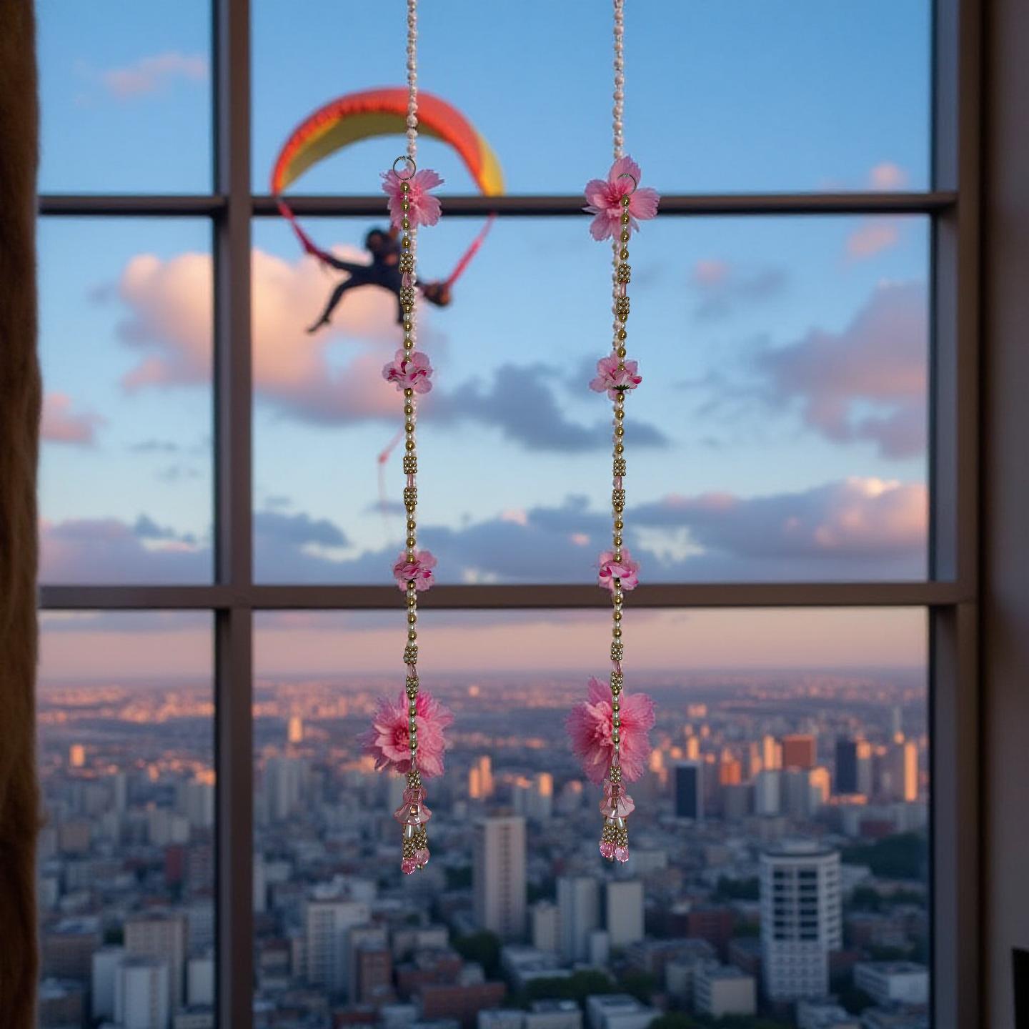 Window view of a cityscape with a person paragliding and decorative earrings with pink flowers.