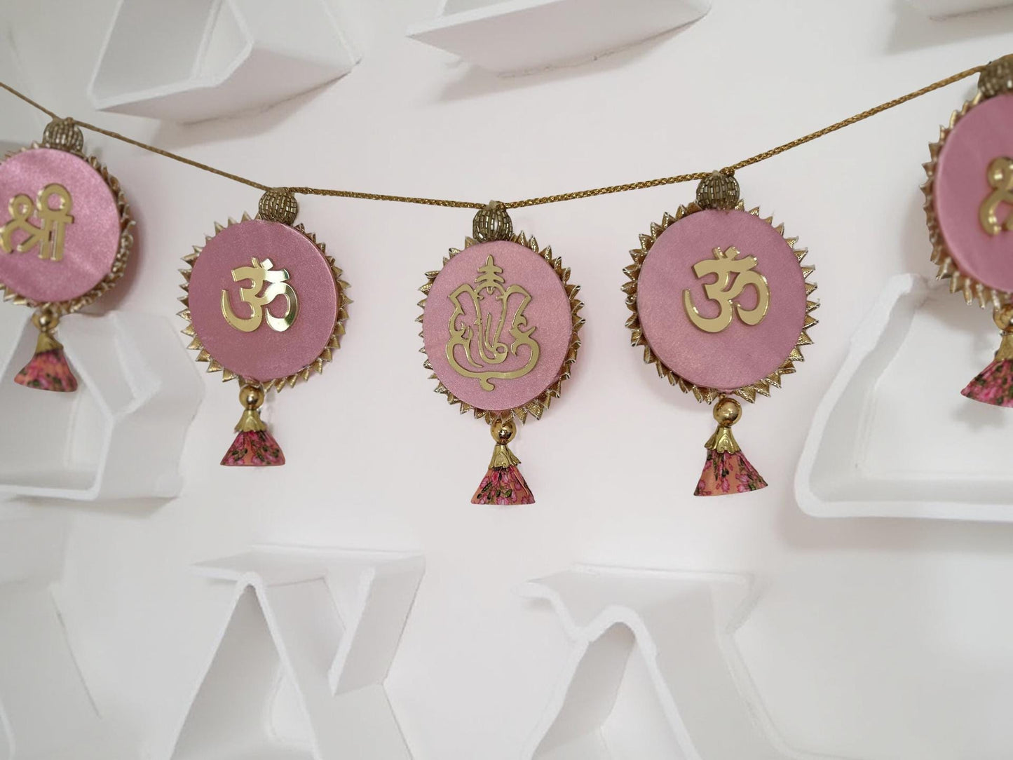 Decorative string with pink pendants featuring gold symbols on a white background