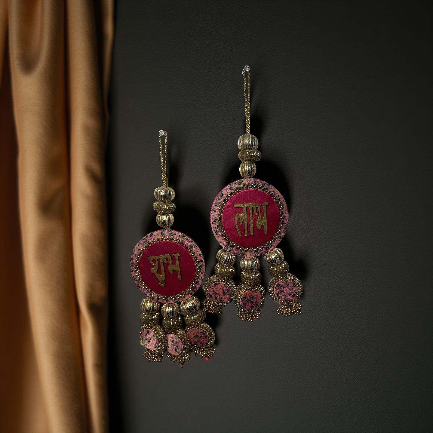 Pair of ornate earrings with pink and gold details on a dark background