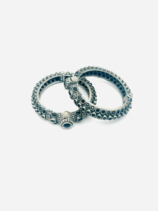 Two silver bangles with black stones on a white background